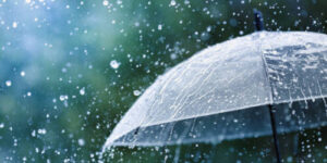 Transparent umbrella under heavy rain against water drops splash background. Rainy weather concept.